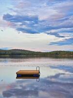 Schwimmen Insel im Schweden auf ein See beim Sonnenuntergang. Wolken reflektiert im das Wasser. foto