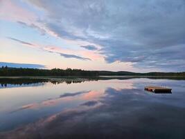 Schwimmen Insel im Schweden auf ein See beim Sonnenuntergang. Wolken reflektiert im das Wasser. foto