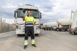 glücklich Erwachsene Mann Mechaniker Stehen im Vorderseite von geparkt LKW im Bedienung Center mit Daumen oben foto