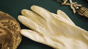 Jahrgang Handschuhe und Schmuck. Lager Filmaufnahme. Nahansicht von Jahrgang Handschuhe und Zubehör Lügen auf Grün Hintergrund. Jahrgang Zubehör im Museum Fenster foto