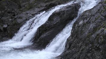 klein schön Wasserfall auf wolkig Tag. Clip. Blau Wasser von klein Wasserfall im Herbst Wald. schön sprudelnd Wasserfall Wasser im Strom auf felsig Terrain foto