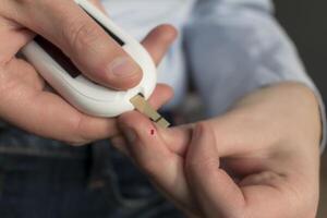 Frau stechend ihr Finger zu prüfen Blut Glucose Niveau mit Glukometer, Prüfung Blut Glucose zum Diabetes foto