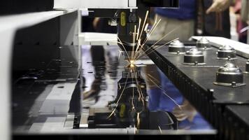 industriell Laser- Maschine Schneiden Metall, Roboter Mechanismus Stichprobe beim das International Ausstellung, Technologie Konzept. Medien. eben Blatt von Metall Stahl Sein Schnitt mit funkelt. foto