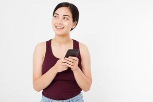 Porträt einer lächelnden jungen koreanischen Frau, die Handy isoliert auf weißem Hintergrund hält, Mädchen im Chat, Werbekonzept, Textfreiraum foto