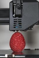 schließen oben von ein 3d Drucker Drucken ein rot polygonal Ei foto