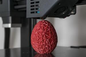 schließen oben von ein 3d Drucker Drucken ein rot polygonal Ei foto