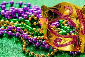 Karnevalsmaske und bunte Perlen auf grün glänzendem Hintergrund. Karneval-Konzept. Fat Tuesday-Symbol. foto