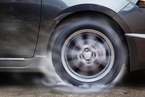 Auto Rennen Spinnen Rad brennt Gummi auf Boden. foto