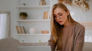 kaukasisch Frau im Brille glücklich Mädchen Dame Schüler Geschäftsfrau Freiberufler weiblich mit Laptop Sitzung auf Couch Sofa beim Zuhause Büro Arbeiten online entfernt Job studieren mit Computer Internet Einkaufen foto