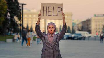 traurig einsam Arm Muslim Mädchen trägt Hijab Frau steht im Stadt suchen beim Kamera demonstriert zeigt an Karton Banner Text Hilfe Bedürfnisse Schutz arbeiten, Arbeitslosigkeit Diskriminierung Problem Konzept foto