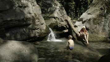 ein Mutter und ihr Sohn Schwimmen im ein Berg Bach im Nord Schweden. kreativ. Konzept von Sommer- Urlaub, kalt Wasser Strom unter Felsen. foto