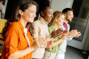 jung multiethnisch Anfang Mannschaft Stehen und applaudieren im das modern Büro foto