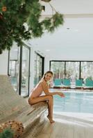 jung Frau entspannend durch das Innen- Schwimmen Schwimmbad foto