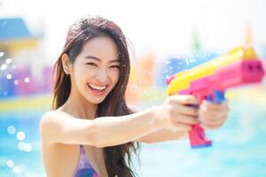 ai generiert ein Frau spielen Wasser Gewehr beim Songkran Tag mit generativ ai foto