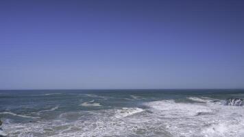 stürmen Meer . Aktion . Blau transparent Wasser Das ist geworfen aus durch Wellen zu das Ufer gegen das Hintergrund von ein Blau wolkenlos Himmel. foto