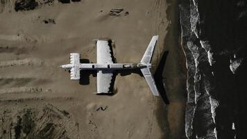 Militär- Geheimnis Flugzeug auf das Ufer von das Meer. Aktion. Antenne oben Aussicht von ein verlassen Flugzeug auf ein Sand Strand. foto