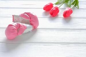 Tulpen Blumen und Boxen Handschuhe auf hölzern Hintergrund, Femenismus Konzept foto