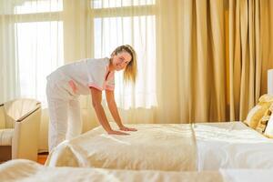 schön Hotel Maid Herstellung Bett im ein Zimmer. foto