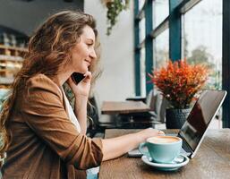 ai generiert Frau haben ein Telefon Anruf während Arbeiten auf ihr Computer foto