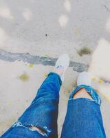 Frau Beine mit Blau Mode Jeans und Weiß Turnschuhe auf Straße foto
