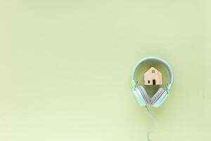 Grün Kopfhörer mit hölzern Haus Modell- auf Grün Hintergrund foto
