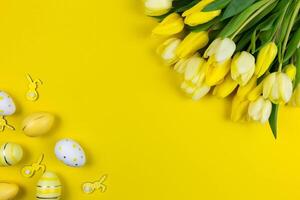 Ostern eben legen mit Gelb Tulpen, bunt Ostern Eier und Hasen Dekoration auf Gelb Hintergrund. oben Sicht. Kopieren Raum. foto