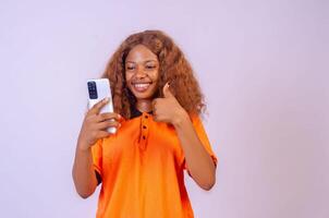 schön jung afrikanisch Frau mit ihr Telefon suchen erstaunt und aufgeregt foto
