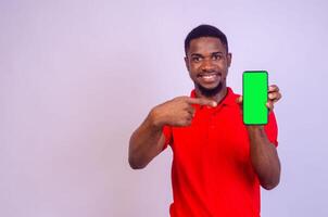 gut aussehend schwarz Mann zeigt an seine Telefon Bildschirm während Gefühl glücklich und aufgeregt, Werbung Konzept, Fokus auf seine Gesicht foto