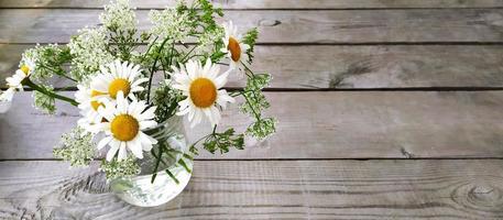 Banner mit einem Strauß Gänseblümchen in einer Vase und Platz für Text. schöne wildblumen sonnige blumen auf einem hölzernen hintergrund. foto