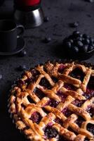 rot Obst Kuchen, Blaubeeren und ein Kaffee Topf platziert auf ein dunkel Hintergrund. foto