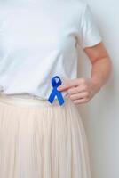 Frau halten Blau Band mit haben Abdomen Schmerz. März kolorektal Krebs Bewusstsein Monat, Dickdarm Krankheit, groß Darm, Geschwür Kolitis, Verdauungs- System und Gesundheit Konzept foto