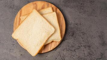 Scheiben von Weiß Brot auf ein hölzern Tafel foto