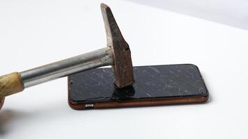 Foto von Smartphone mit Hammer auf oben von gebrochen Berührungssensitiver Bildschirm Anzeige auf Weiß Hintergrund