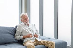 Senior Mann mit Bauch schmerzen, unzufrieden Mann drückt seine Hand zu Bauch von unerträglich Schmerz, reifen Mann mit Bauch Schmerzen Gefühl nicht wohl Sitzung im Leben Zimmer foto