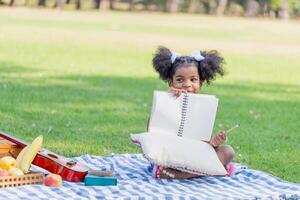 Kind Mädchen spielen draußen, süß wenig Mädchen spielen im das Garten, glücklich Kind zeigen Buch foto