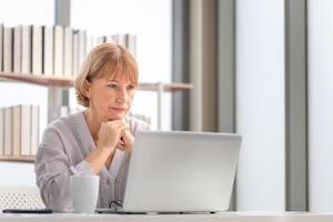 reifen Frauen mit Laptop Computer Überprüfung ihr Rechnungen, Frau lesen Unterlagen, reifen Frau im Leben Zimmer mit Laptop foto