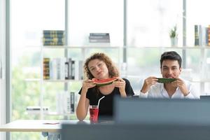 Zwei Büroangestellte trinken Wasser und essen Wassermelone foto