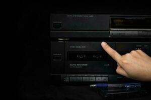 Die Hand einer Frau, die eine Kompaktkassette in das Audio des alten Players einfügt, ist Retro-Technologie foto