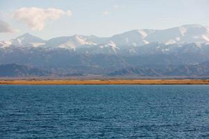 Blau Ruhe Wasser im issyk-kul See mit Berge auf Hintergrund beim Herbst Nachmittag foto