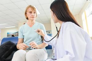 Ärztin verwendet ein Stethoskop, um die alte Patientin im Krankenhaus zu überprüfen. foto