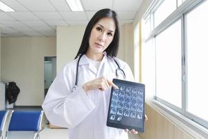 Porträt einer intelligenten Ärztin, die ein Tablet hält, um ein Röntgenbild zu zeigen und an der Rezeption des Krankenhauses steht. foto