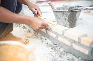 Professioneller Arbeiter, der Pfannenmesser zum Bauen von Ziegelwänden mit Zement und Mörtel verwendet