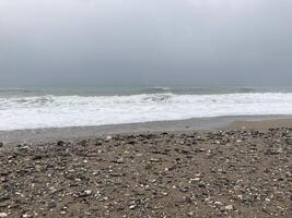 das turbulent Meer Stürme das Ufer von Sand gemischt mit Kieselsteine foto