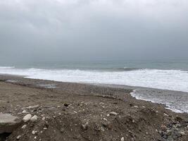 das turbulent Meer Stürme das Ufer von Sand gemischt mit Kieselsteine foto