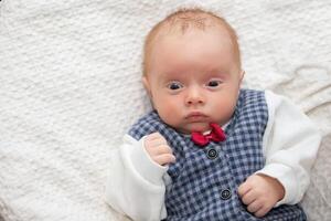 Porträt von ein Neugeborene Baby tragen ein elegant Weste mit ein rot Bogen binden. foto