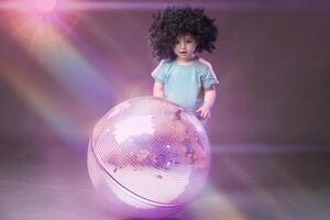 ein wenig komisch Mädchen sieht aus mit Bewunderung beim ein glänzend Rosa Disko Ball. foto