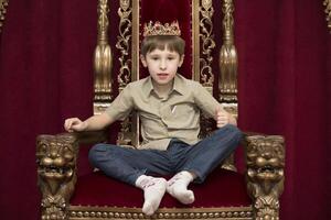 ein Kind mit ein Krone im das königlich Stuhl foto