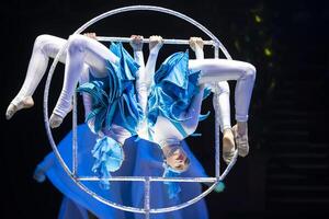 zwei Akrobat Mädchen Show ein Zirkus Nummer auf ein dunkel Hintergrund. akrobatisch Leistung. foto