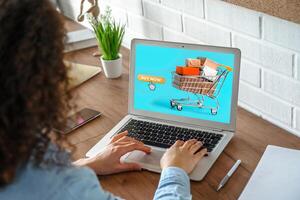 Mädchen Einkaufen online mit Laptop Computer Sitzung drinnen. Internet Geschäft Konzept. foto