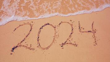 2024 Jahr Botschaft handgeschrieben im Sand auf Strand Hintergrund. Neu Jahre Konzept. foto